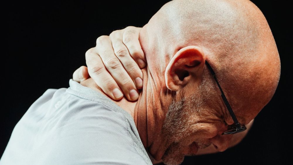 Office worker holding neck in pain, a common chronic pain complaint in Plano TX
