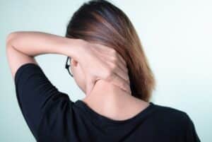 Woman holding her neck and shoulders due to fibromyalgia chronic pain syndrome