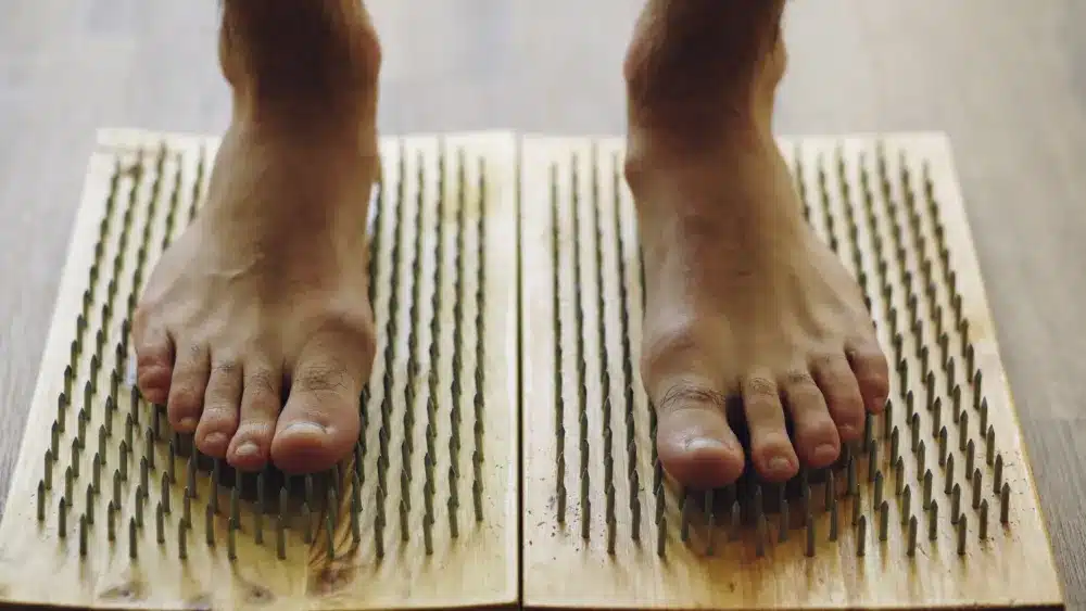 Person holding foot experiencing neuropathy tingling and burning nerve pain symptoms