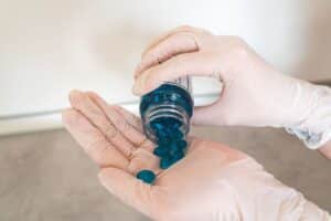 Melatonin supplement bottle beside a glass of water for chronic pain and sleep relief