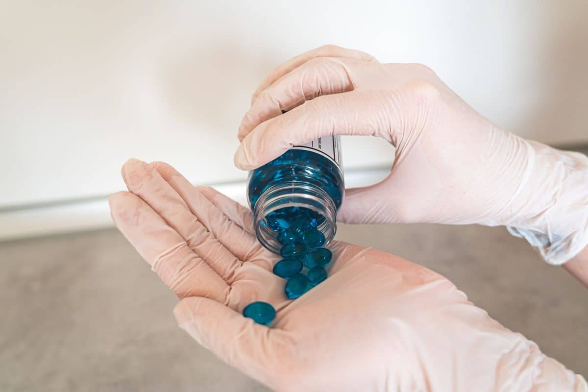 Melatonin supplement bottle beside a glass of water for chronic pain and sleep relief