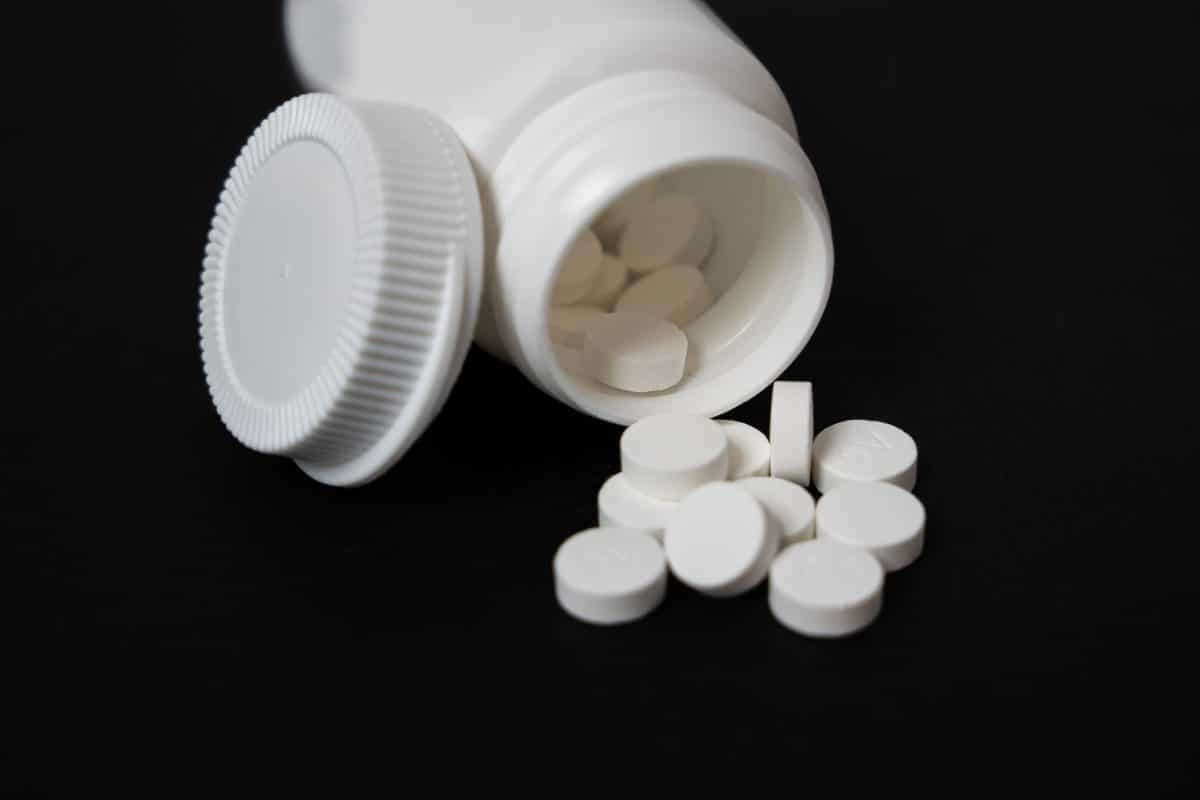 Melatonin supplement capsules beside a sleep mask suggesting chronic pain and sleep relief