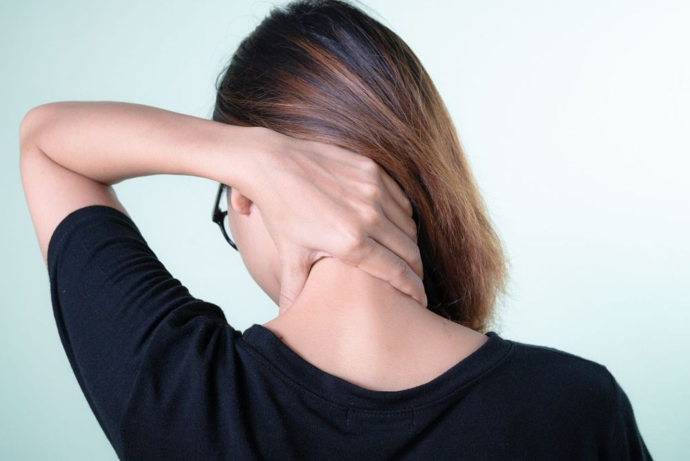 Woman holding her neck experiencing chronic head and neck pain at home